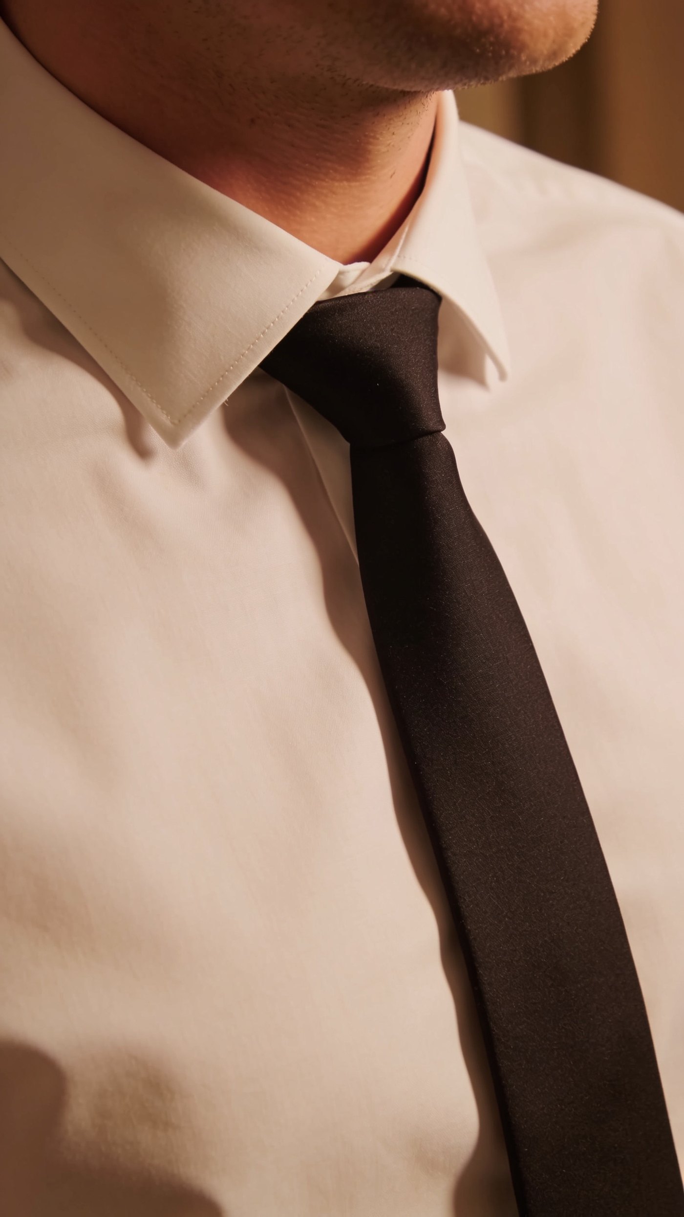 A slim dark tie matched to the lapel width over a white shirt