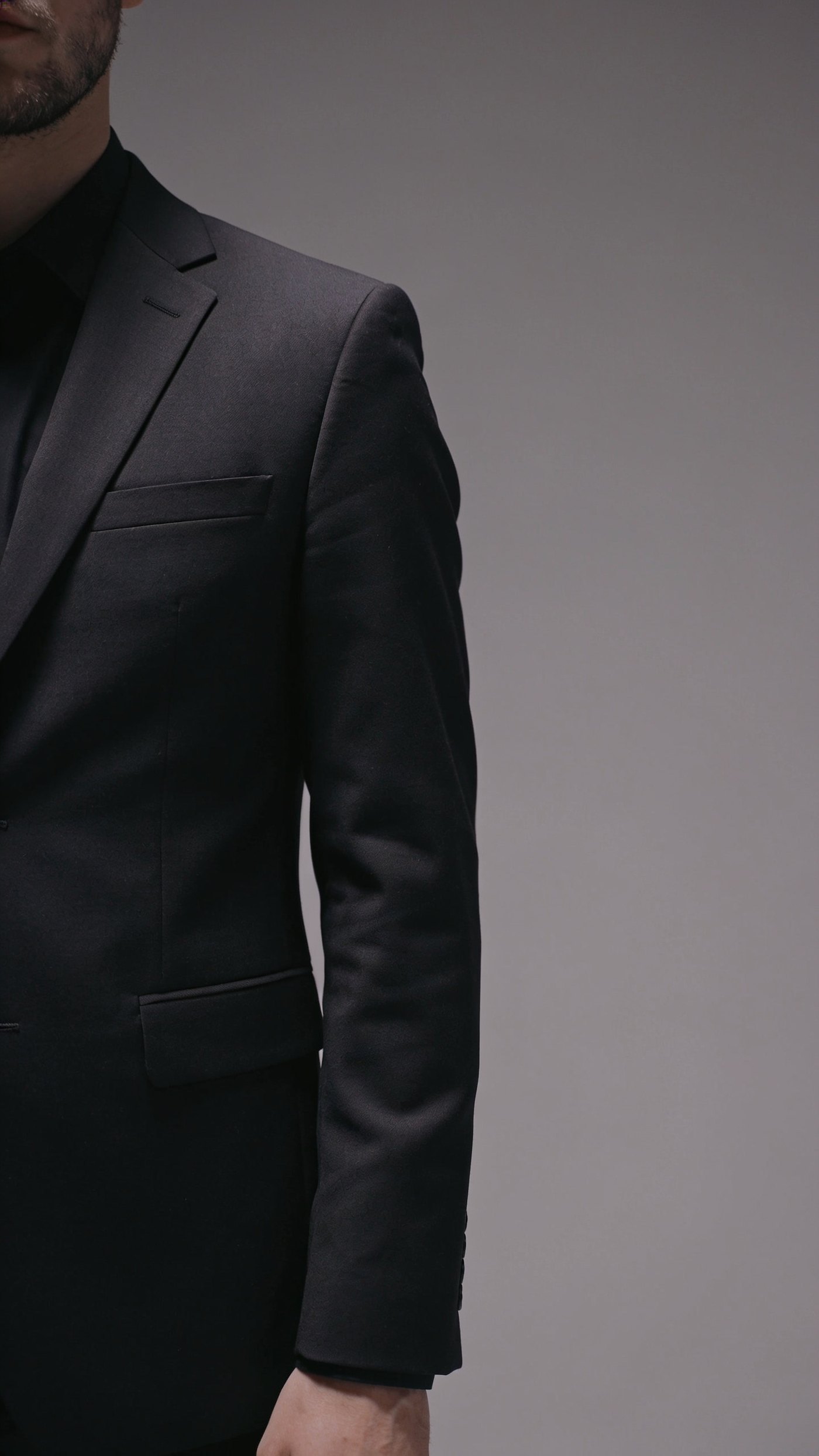 A dark suit cut close through the shoulder, chest and waist