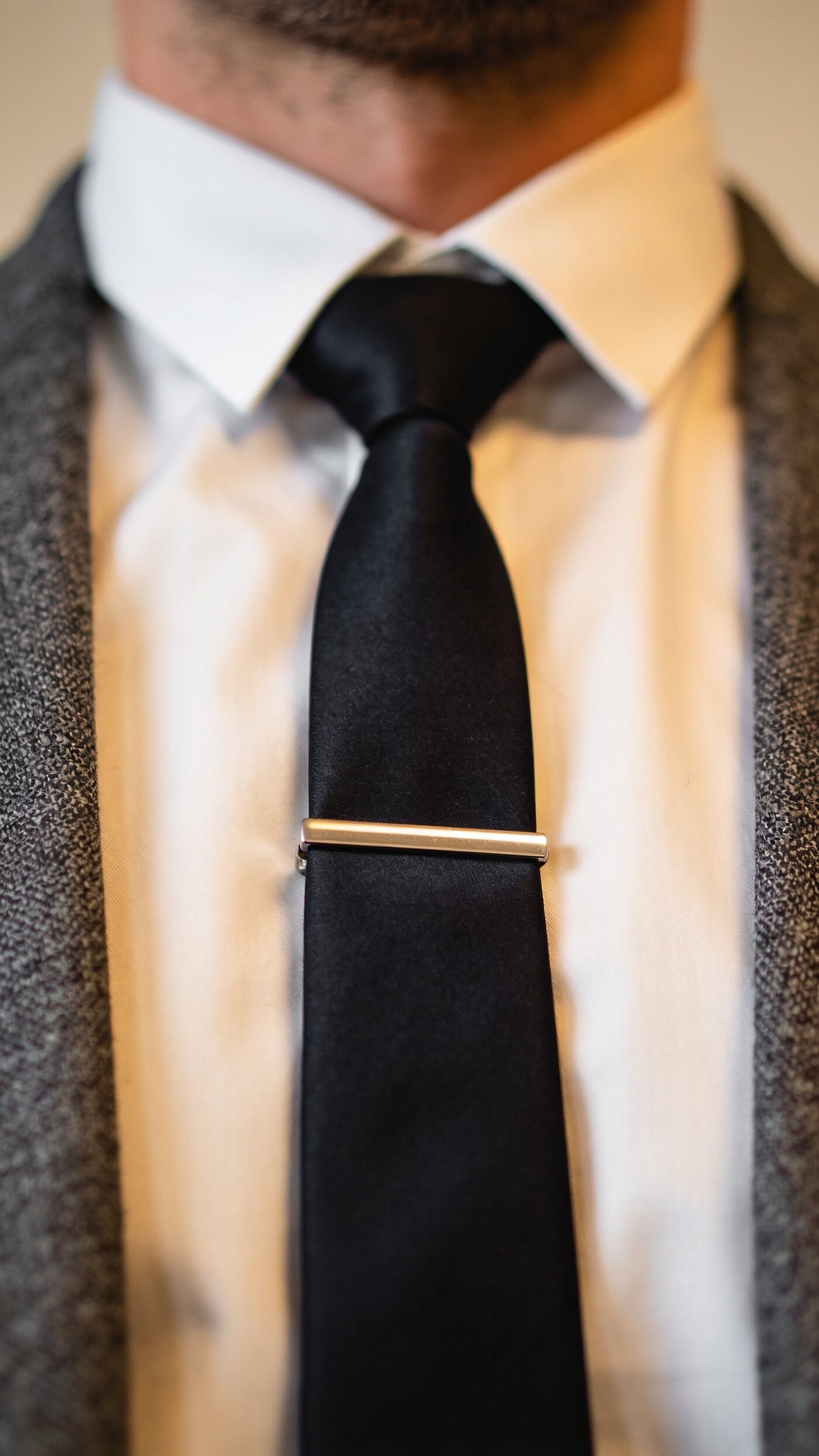 A plain metal tie bar holding a tie flat against a shirt placket