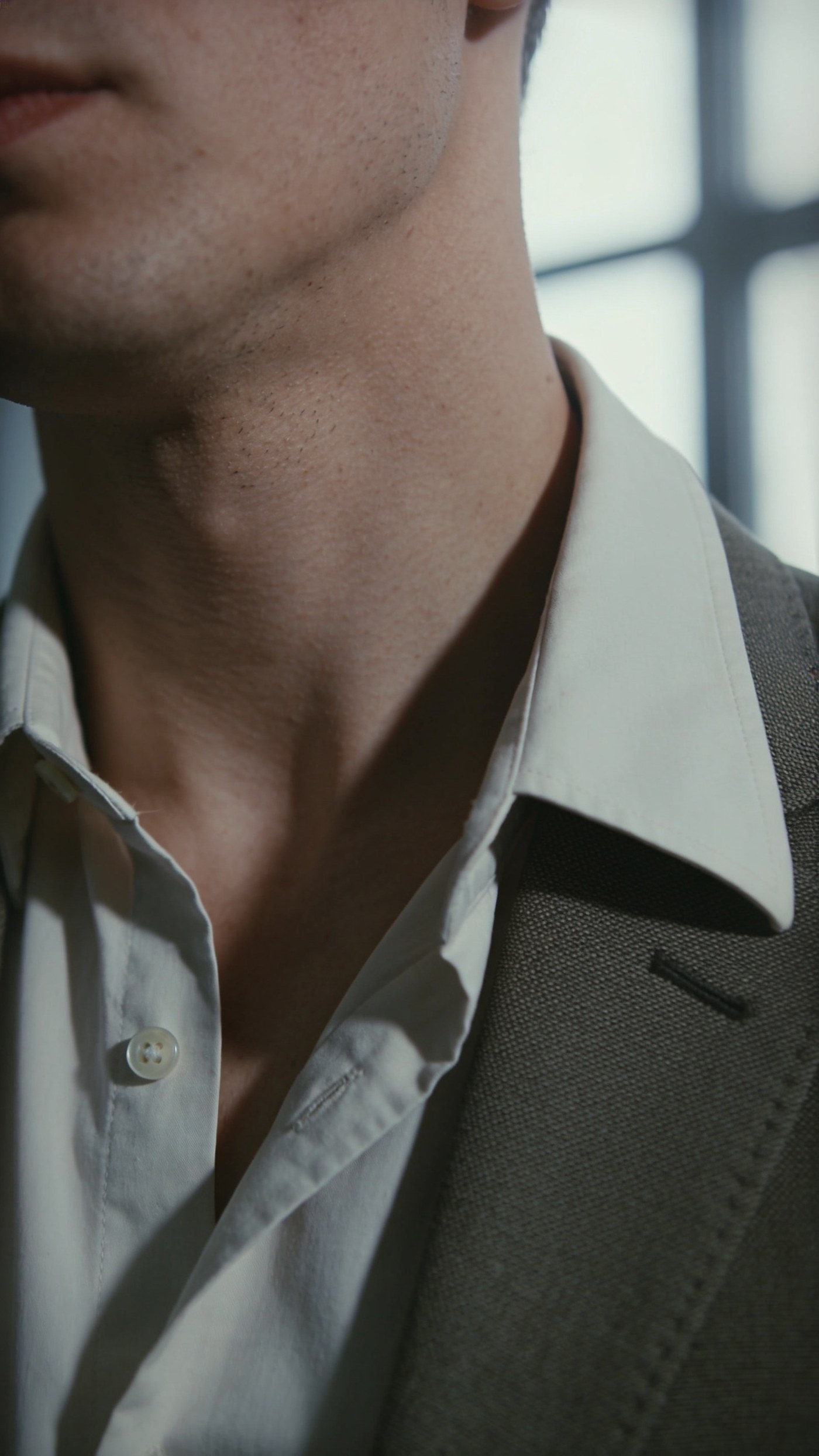 A structured open shirt collar standing without a tie beneath a jacket lapel