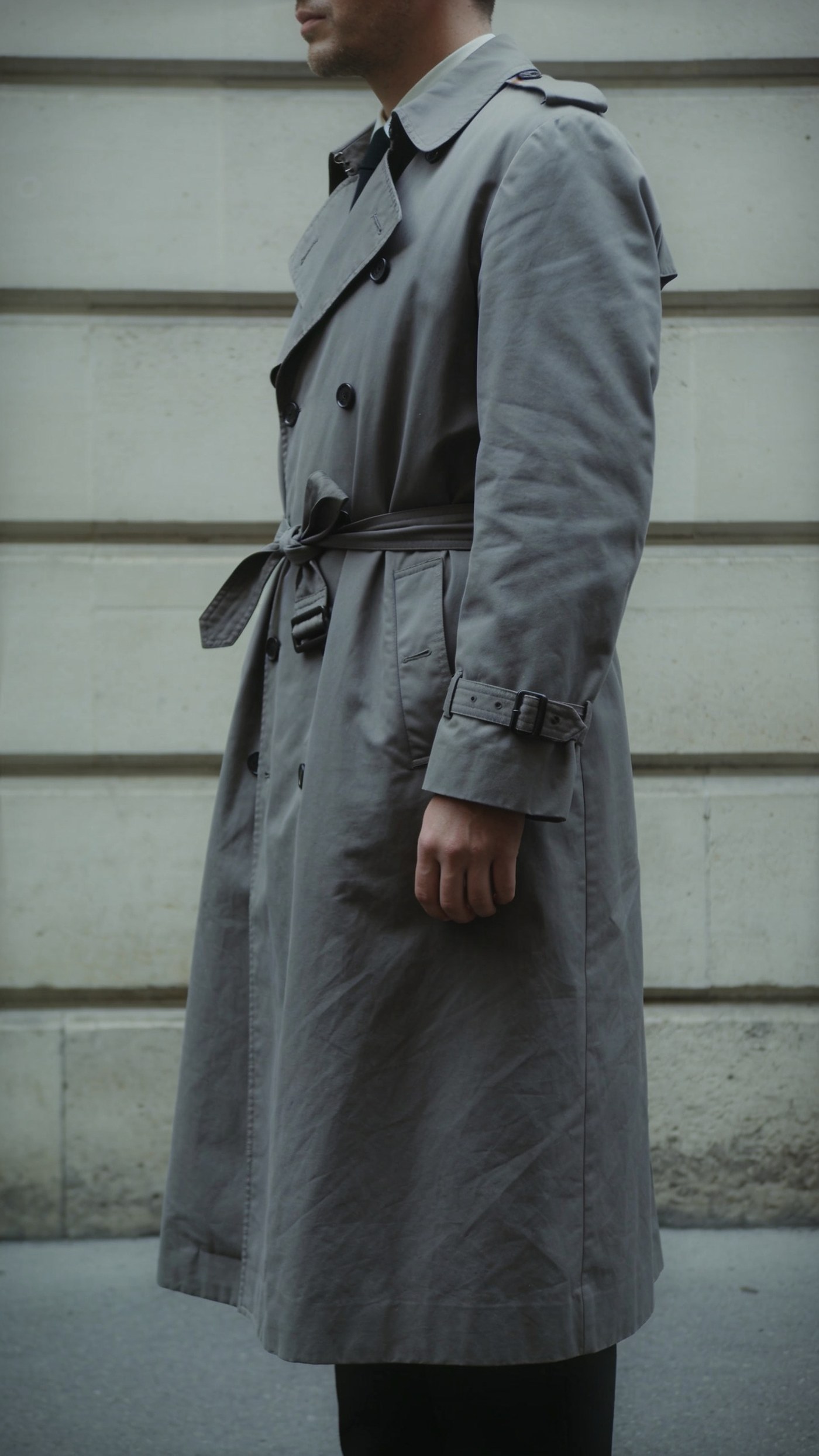 A long belted trench coat carrying one line past the knee